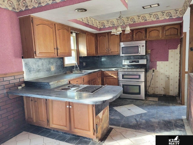 kitchen featuring brick wall, stainless steel appliances, sink, and kitchen peninsula