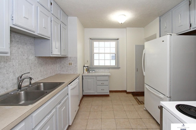 kitchen with white appliances, light tile patterned flooring, sink, a textured ceiling, and white cabinets