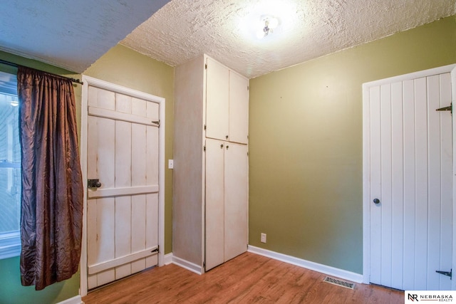 unfurnished bedroom with a textured ceiling and light wood-type flooring