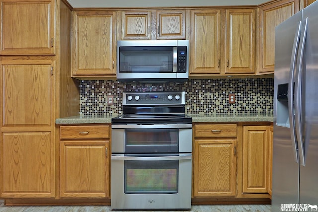 kitchen featuring appliances with stainless steel finishes, decorative backsplash, and light hardwood / wood-style floors