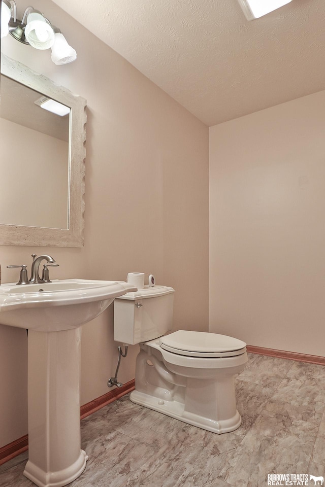 bathroom featuring a textured ceiling and toilet