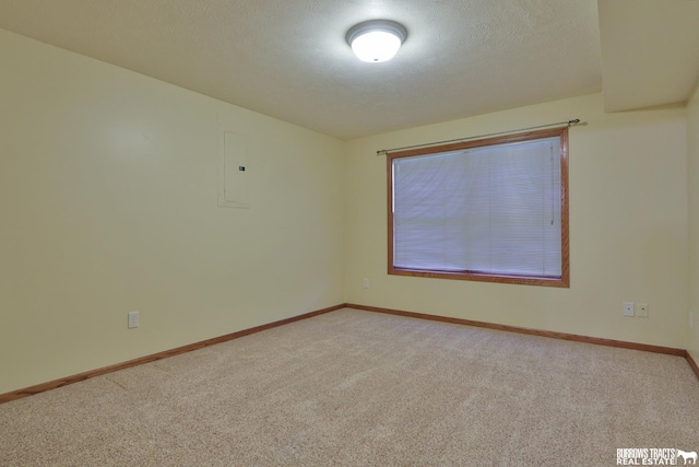 empty room with electric panel, a textured ceiling, and carpet floors