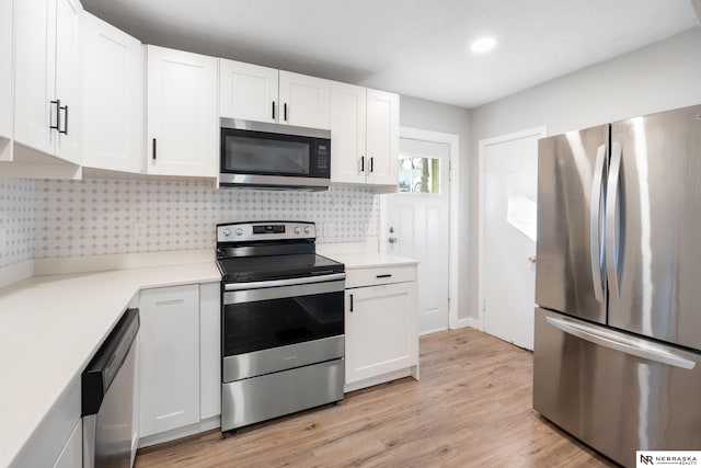 kitchen with white cabinetry, stainless steel appliances, light wood-type flooring, and backsplash