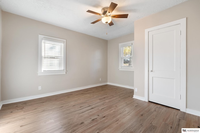 empty room with light hardwood / wood-style flooring, a textured ceiling, and a wealth of natural light