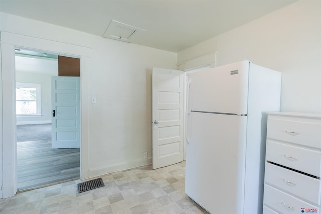 kitchen with white cabinets, white fridge, and light hardwood / wood-style floors