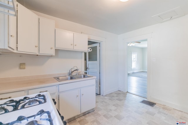 kitchen with white range with gas cooktop, white cabinetry, and sink