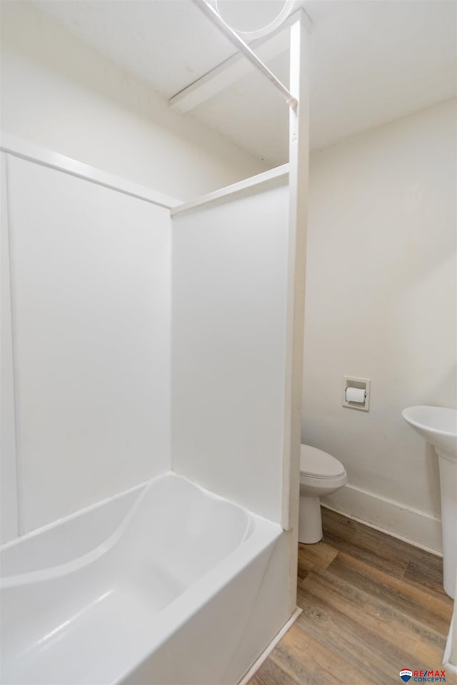 bathroom with toilet, hardwood / wood-style flooring, and shower / bathtub combination