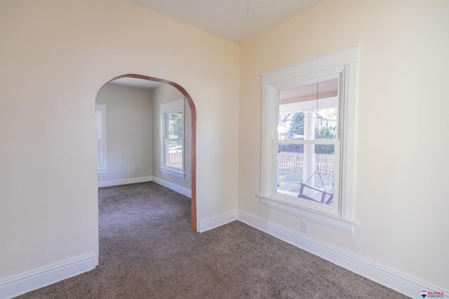 spare room with a healthy amount of sunlight and dark carpet