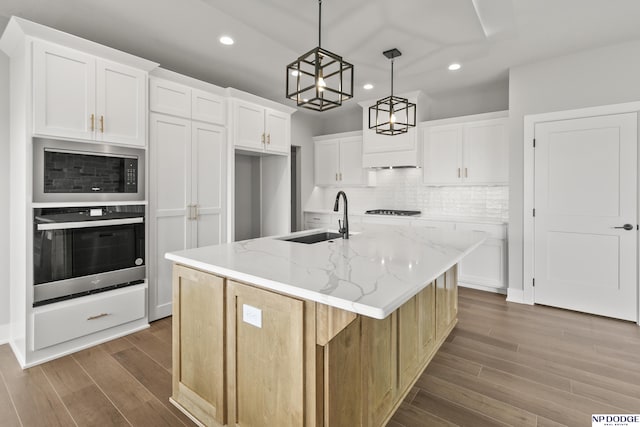 kitchen featuring a sink, wood finished floors, stainless steel oven, decorative backsplash, and built in microwave