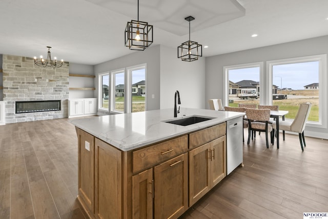 kitchen with dishwasher, a sink, pendant lighting, and wood finished floors