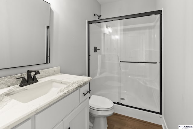 full bath featuring toilet, vanity, a stall shower, and wood finished floors