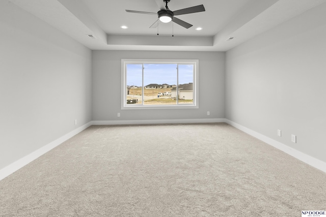 carpeted empty room with a tray ceiling, baseboards, and recessed lighting