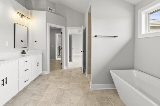bathroom with a freestanding tub, baseboards, double vanity, visible vents, and a sink