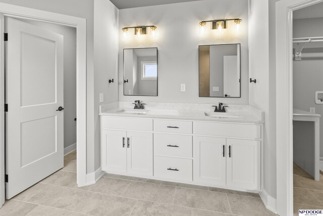 bathroom featuring double vanity, a sink, and baseboards