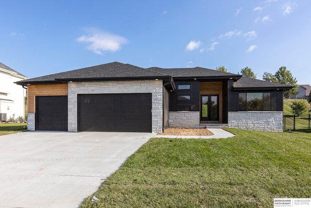 prairie-style home with cooling unit, a front lawn, and a garage