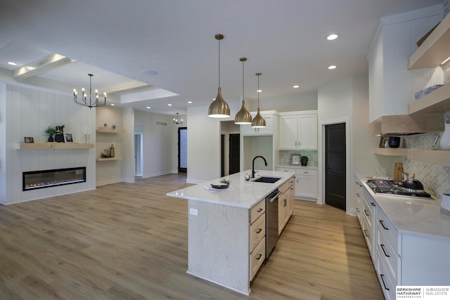 kitchen with sink, an island with sink, white cabinetry, and light hardwood / wood-style floors