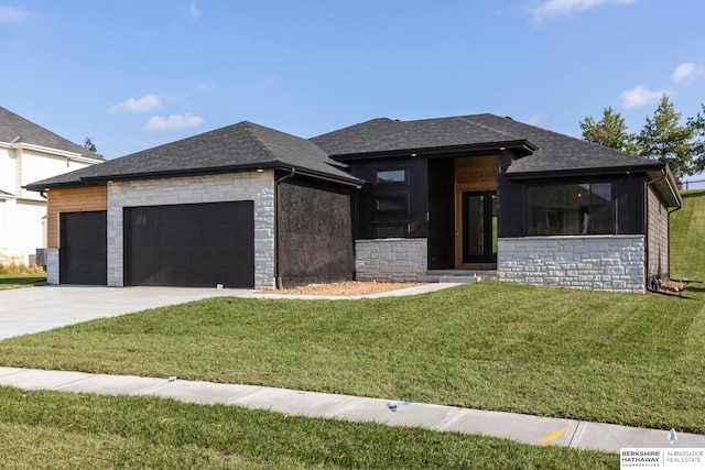 prairie-style house featuring a garage and a front lawn