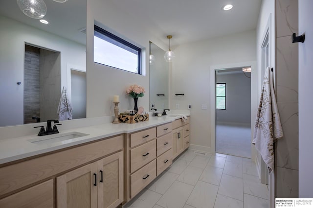 bathroom with vanity, tiled shower, and a wealth of natural light