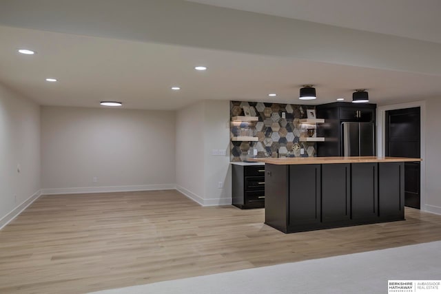 bar with stainless steel fridge and light hardwood / wood-style floors