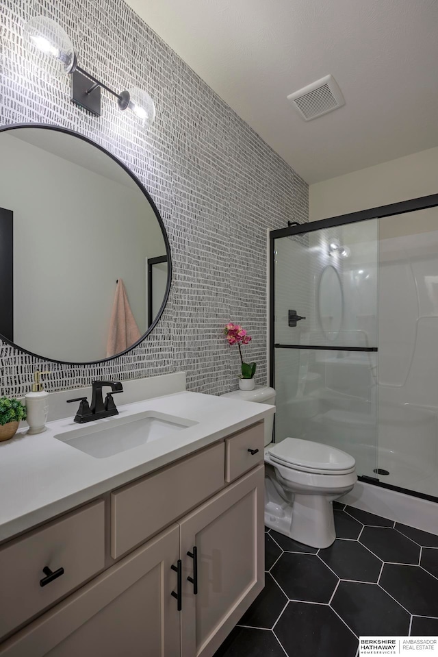 bathroom featuring tile walls, toilet, vanity, an enclosed shower, and tile patterned floors