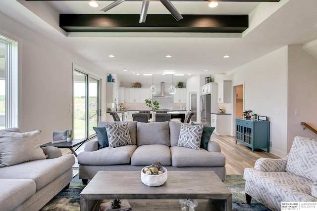 living room with sink, light hardwood / wood-style flooring, and a tray ceiling