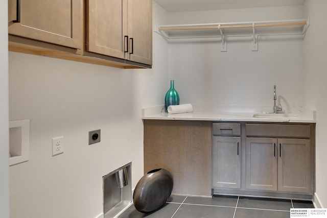 clothes washing area with sink, cabinets, hookup for an electric dryer, and dark tile patterned floors