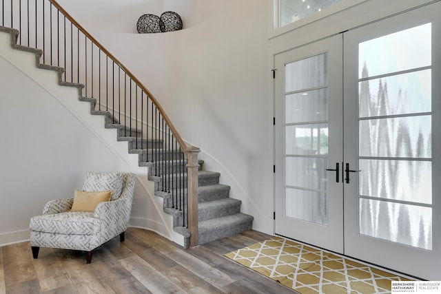 entrance foyer featuring french doors, a towering ceiling, and wood-type flooring