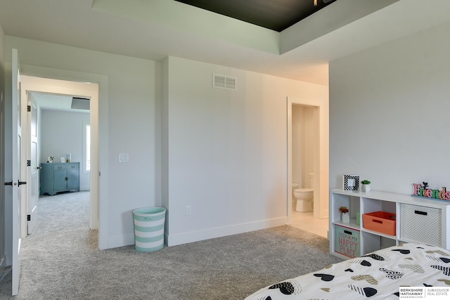 bedroom with ensuite bathroom and light colored carpet