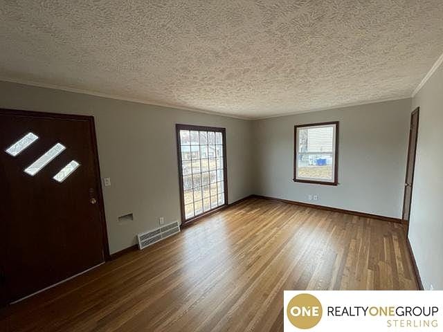 foyer featuring ornamental molding, a textured ceiling, hardwood / wood-style flooring, and a healthy amount of sunlight