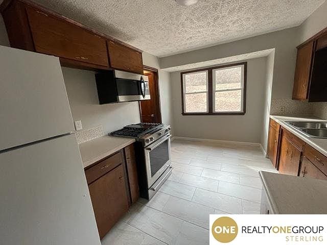 kitchen with appliances with stainless steel finishes, a textured ceiling, and sink