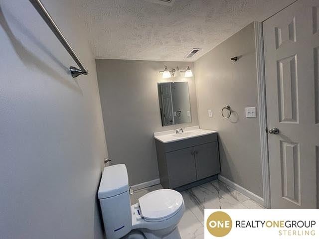 bathroom featuring toilet, a textured ceiling, and vanity