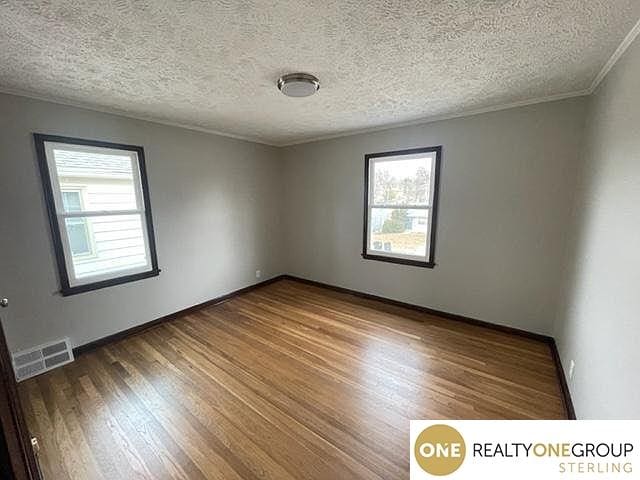 spare room with crown molding, hardwood / wood-style flooring, and a textured ceiling