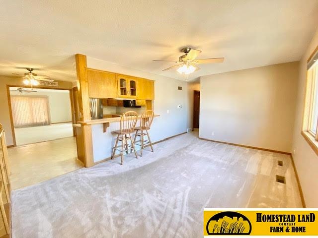 kitchen featuring light carpet, stainless steel fridge, a wealth of natural light, and a breakfast bar area