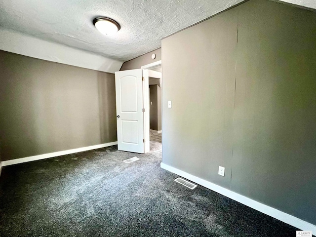 unfurnished room featuring a textured ceiling, lofted ceiling, and dark colored carpet