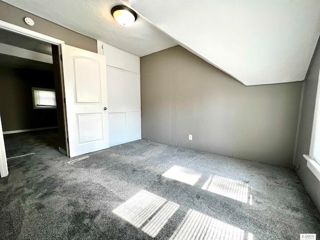 additional living space featuring vaulted ceiling and dark colored carpet