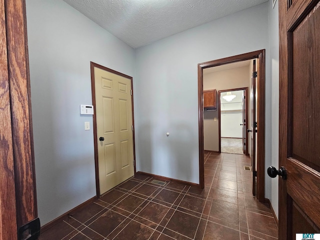 hall with dark tile patterned floors and a textured ceiling