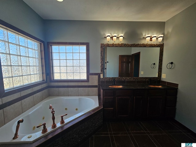 bathroom featuring vanity, tiled bath, a textured ceiling, and tile patterned flooring