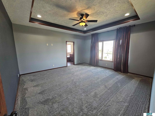 spare room with a textured ceiling, ceiling fan, carpet flooring, and a raised ceiling