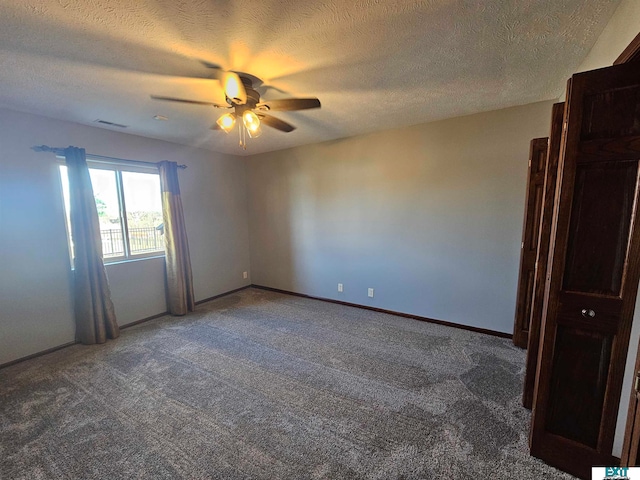 spare room with dark carpet, a textured ceiling, and ceiling fan