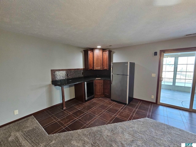 kitchen featuring stainless steel fridge, a textured ceiling, and dark tile patterned flooring