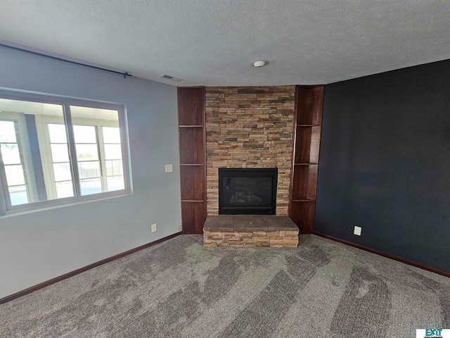 unfurnished living room featuring a textured ceiling, a stone fireplace, and carpet floors