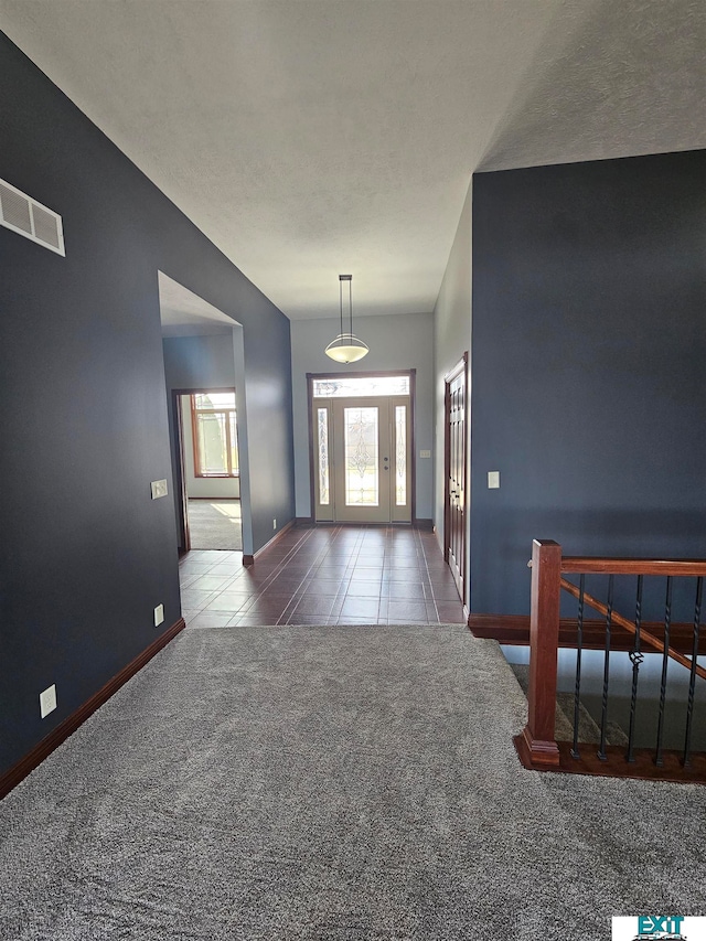 carpeted foyer with a textured ceiling