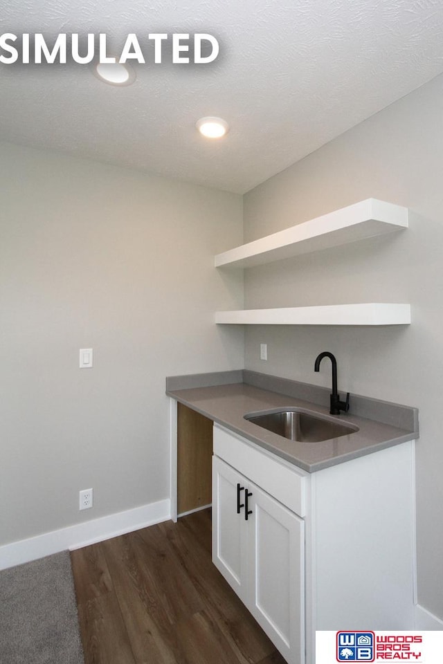 bar featuring a textured ceiling, white cabinetry, dark wood-type flooring, and sink