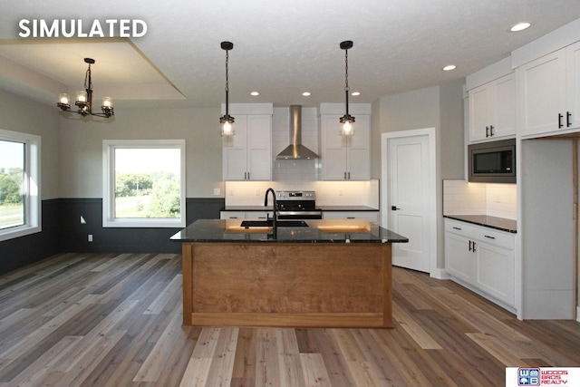 kitchen featuring white cabinetry, a center island with sink, wall chimney exhaust hood, and appliances with stainless steel finishes