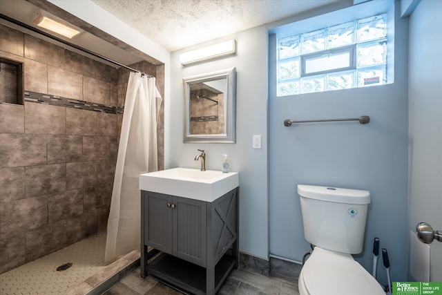 bathroom with vanity, curtained shower, a textured ceiling, and toilet