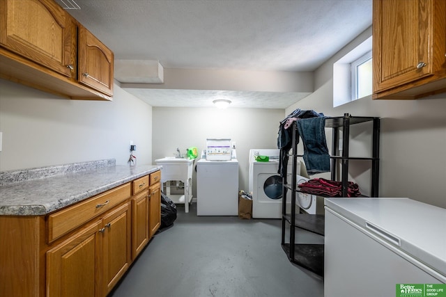 washroom with cabinets, a textured ceiling, sink, and washing machine and clothes dryer