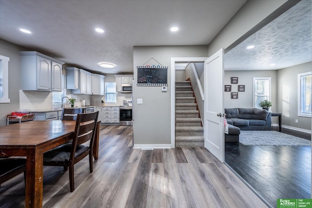 kitchen with light hardwood / wood-style flooring, gray cabinetry, appliances with stainless steel finishes, a textured ceiling, and tasteful backsplash