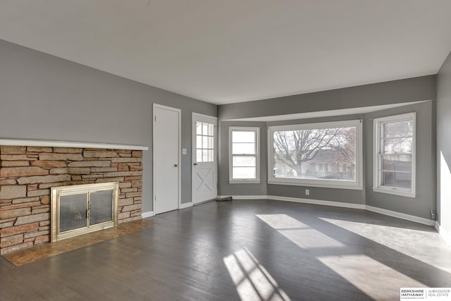 unfurnished living room with a stone fireplace and dark hardwood / wood-style floors