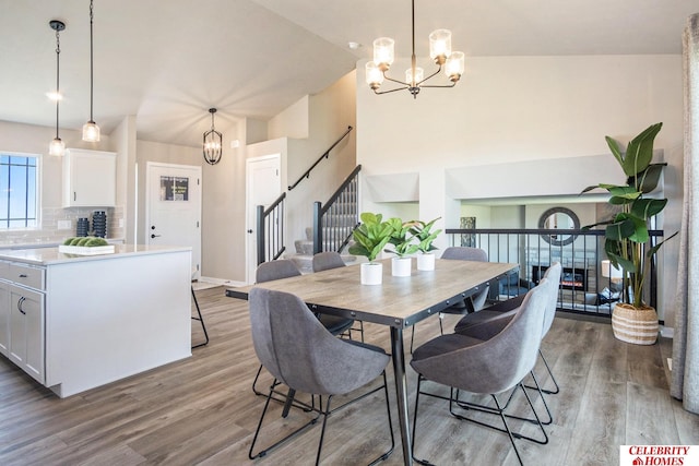 dining room with high vaulted ceiling, hardwood / wood-style flooring, and an inviting chandelier