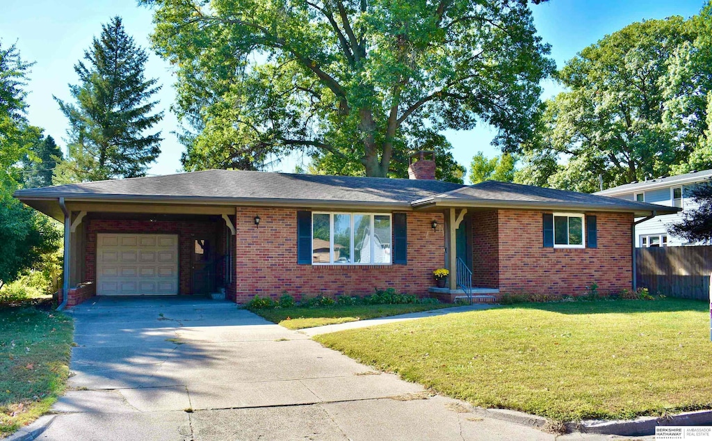 single story home featuring brick siding, a chimney, concrete driveway, an attached garage, and a front yard